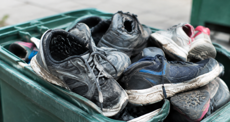 Chaussures abimees empilees dans un bac de recyclage